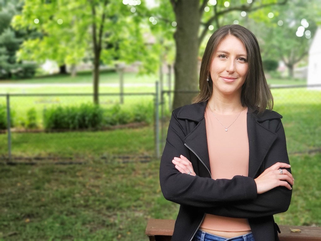Lauren Slagter: woman with dark shoulder-length hair, black jacket, standing with arms crossed.